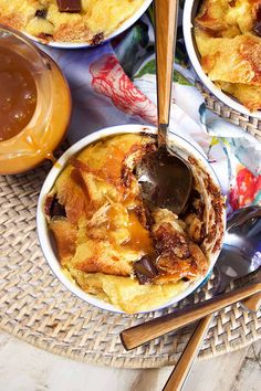 two bowls filled with food on top of a woven place mat next to utensils