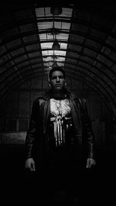 black and white photograph of a man standing in a dark tunnel with his hands on his hips