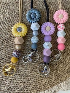 four key chains with flowers on them hanging from a straw hat purse bag holder,