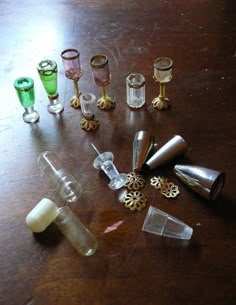 several different sized and colored glass items on a wooden table with one candle holder in the middle