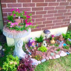 there is a small garden with flowers and plants in the ground next to a brick wall