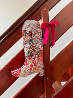 a pair of boots hanging from the side of a wooden stair case with pink ribbon