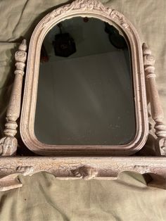 an old mirror sitting on top of a bed