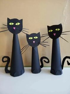 three black paper cats are standing next to each other