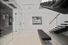 an empty room with a bench and wine rack on the wall next to stairs that lead up to a second floor