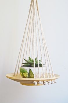 a hanging planter with succulents and plants in it on a wooden shelf