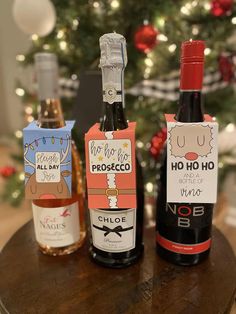 three bottles of wine sitting on top of a wooden table next to a christmas tree