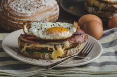 a breakfast sandwich with eggs, ham and cheese on it sitting on a white plate