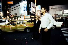 a man and woman standing in front of a taxi