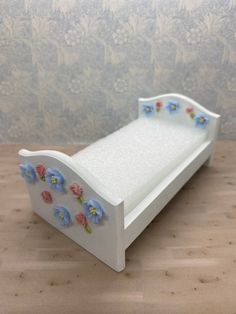 a white wooden bed with flowers on the side and blue flowers on the sides, against a wallpapered background