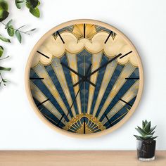 a wall clock with an art deco design on it's face next to a potted plant