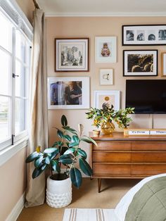 a living room with pictures on the wall and a dresser in front of it next to a bed