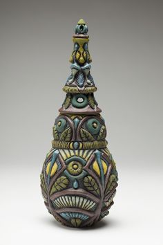 a decorative vase is sitting on a white surface with an intricate design in the center