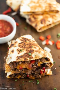 two quesadillas cut in half on a cutting board with sauce and pepper