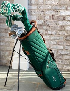 a green golf bag sitting on top of a wooden stand next to a brick wall