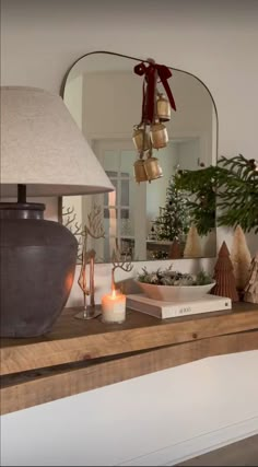 a table with a lamp, mirror and other items on it in front of a christmas tree