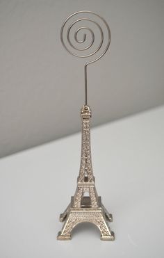 a small metal model of the eiffel tower on a white surface with a spiral design