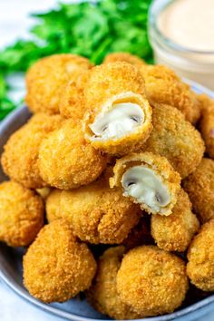 some fried food is in a bowl with dipping sauce on the side and parsley