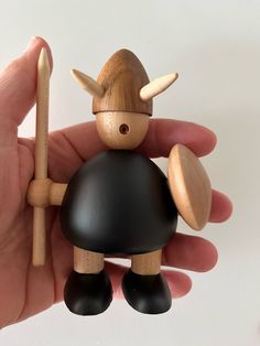 a hand holding a small wooden toy with horns on it's head