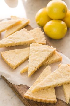 lemons and crackers on a cutting board next to some lemons in the background