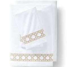 white sheets with gold trim on them and two pillow cases in the same color scheme