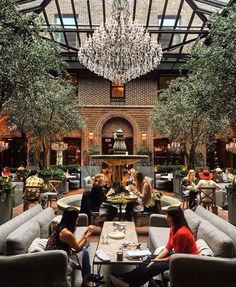 people are sitting at tables in the middle of a large room with chandelier