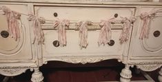 an antique white dresser with pink ribbons on it