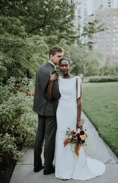 a bride and groom standing on the sidewalk