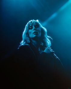 a woman with blonde hair standing in front of blue lights