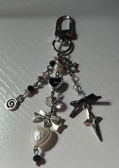 a keychain with charms attached to it on a white surface, including an angel and heart