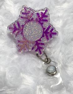 Design:  Glittered Snowflake Holographic (pinks) Badge Reels an excellent gift or addition to your scrubs, shirt pocket, belt loop, lanyard, and more. They are a great gift choice for nurses, medical staff, office staff, and anyone who is required to wear a badge This Badge Reel is:  - Approx 2" in size - Hand glittered with permanent Vinyl design and sealed with Epoxy Resin for added protection against wear and tear  - The badge is adhered to an alligator swivel spring clip which can clip to anything that the clip can pinch. The swivel clip also turns in 360 degrees which reduces the wear and tear on the 34" retractable nylon cord.   *PLEASE NOTE: Placing multiple IDs and other items may place additional strain or weight on the reel which may contribute to the reel failing to retract. Ret Scrubs Shirt, Office Staff, Medical Staff, Shirt Pocket, Retractable Badge Reel, Pocket Belt, Permanent Vinyl, Vinyl Designs