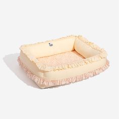 an infant's bed with ruffled edges and a pillow in the shape of a rectangle