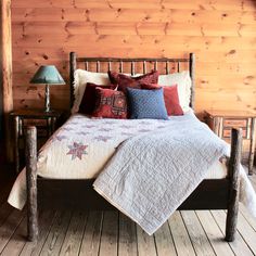 a bed with pillows and blankets on it in a room that has wood paneled walls