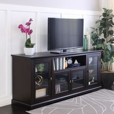 a flat screen tv sitting on top of a wooden entertainment center next to a potted plant