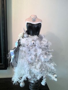 a mannequin is dressed up in white and silver for the christmas tree display