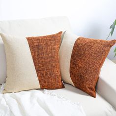 two brown and white pillows sitting on top of a couch next to a potted plant