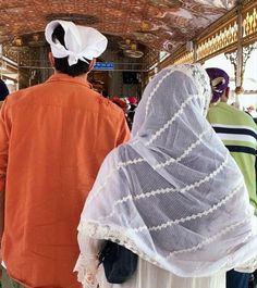 a man and woman are walking down the street in veils on their heads as people look on