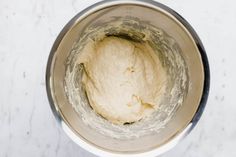 a metal mixing bowl filled with dough on top of a white counter