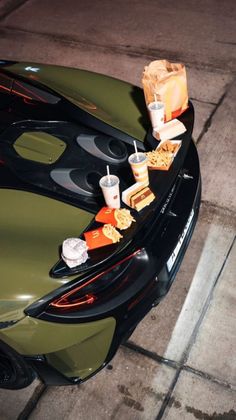 a car with food and drinks on the hood