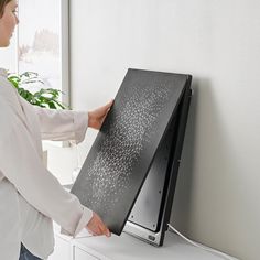 a woman is holding the screen up against the wall