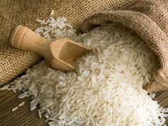 white rice in a sack next to a wooden scoop