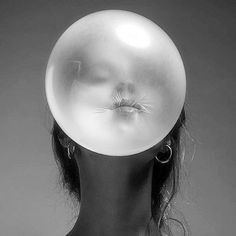 a woman's head with an object in the shape of a bubble over her face