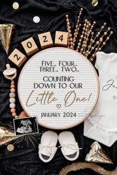 a cross stitch baby announcement is displayed on a black blanket with gold confetti