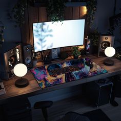 a computer desk with speakers and a keyboard on it in front of a large screen