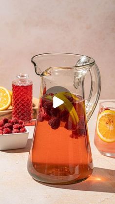 a pitcher filled with raspberries and lemons on top of a table next to bowls