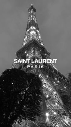 the eiffel tower lit up at night in black and white with text that reads saint laurent paris