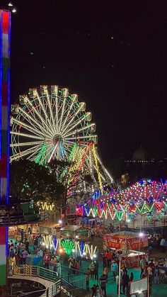 an amusement park at night with ferris wheel lit up