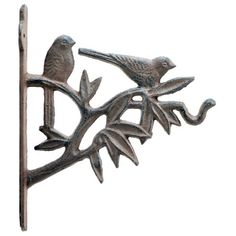 two birds are perched on the branch of a metal tree ornament with leaves