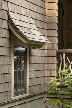 an open window on the side of a wooden house with a metal awning over it