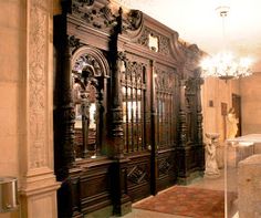 an ornately carved wooden cabinet in the middle of a room with chandelier